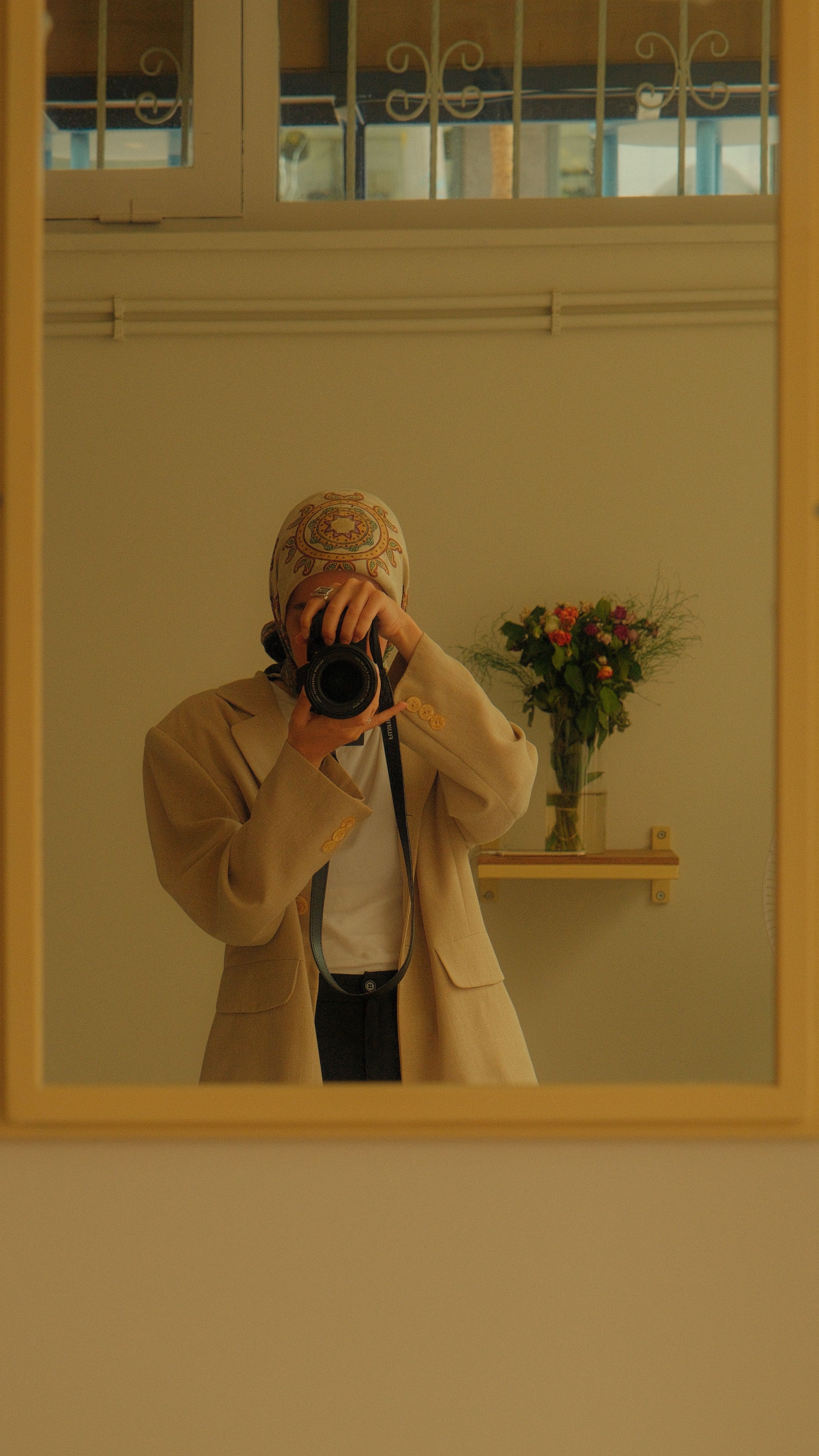 Stylish woman captures her reflection in a mirror with a DSLR, showcasing a creative self-portrait.