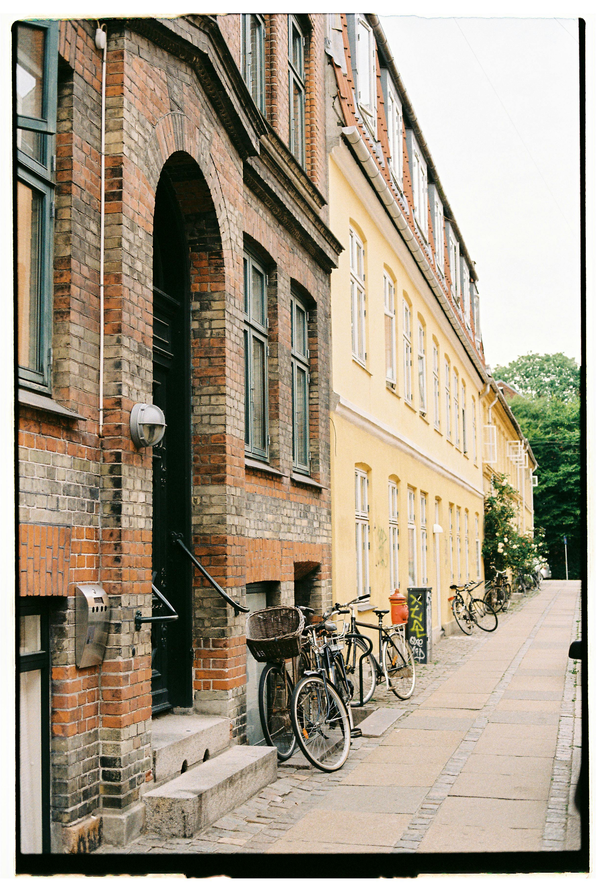 Picturesque urban street view featuring bicycles lined up against colorful brick buildings.