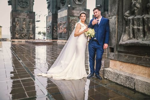 Free A captivating outdoor wedding photo featuring a bride in a stunning gown and a groom in a blue suit. Stock Photo