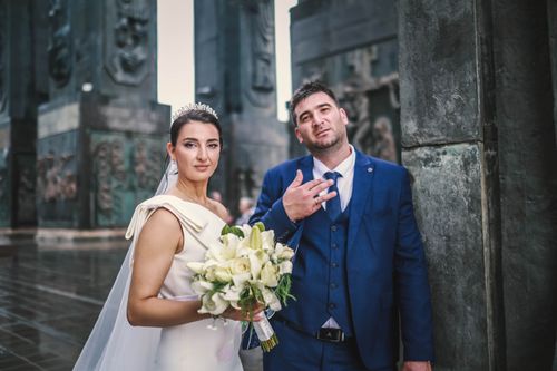 Free Bride and groom elegantly posing near a grand monument on their special day. Stock Photo
