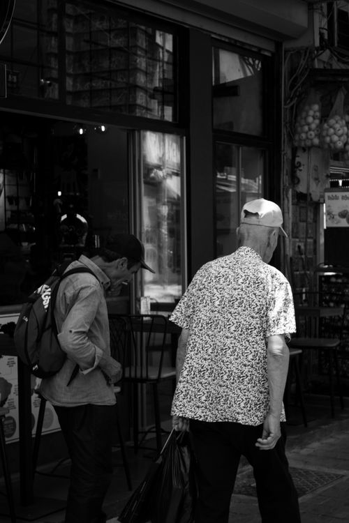 Free Two men walking past shops on an urban street in a black and white photo. Stock Photo
