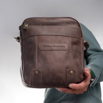 Stylish Gino Bigioni leather shoulder bag showcased by hand for modern fashion lovers.