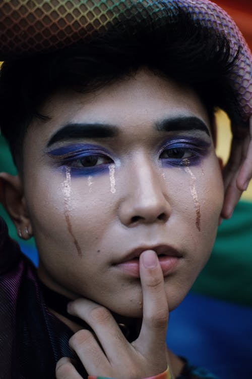 Man With Blue Eyeshadow Touching His Lips in Closeup Photo