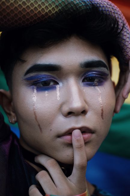 Intense portrait of a young man with bold eye makeup and dramatic expression.