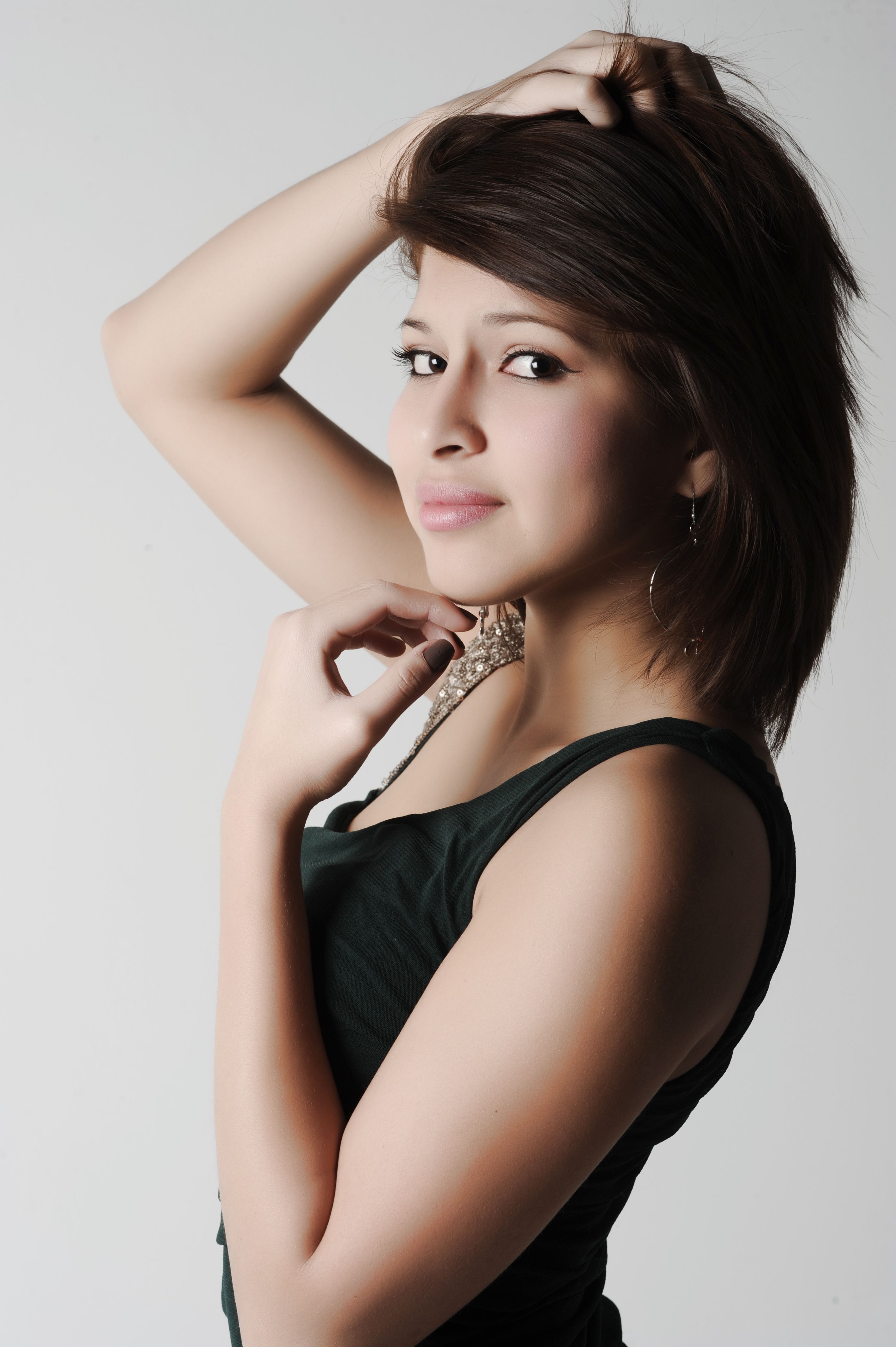 Portrait of a woman with brunette hair posing elegantly in a studio setting.