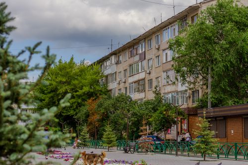Free Residential area with apartment buildings, street trees, and people walking. Stock Photo