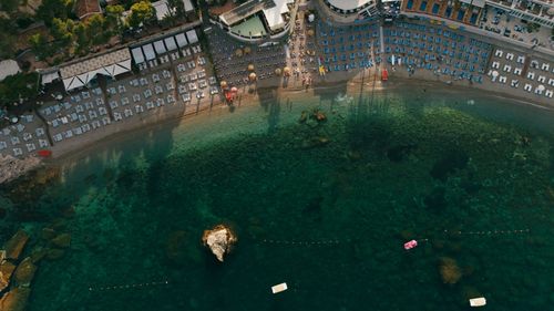 Free Drone shot capturing a picturesque beachfront resort with sunbeds and clear sea water. Stock Photo