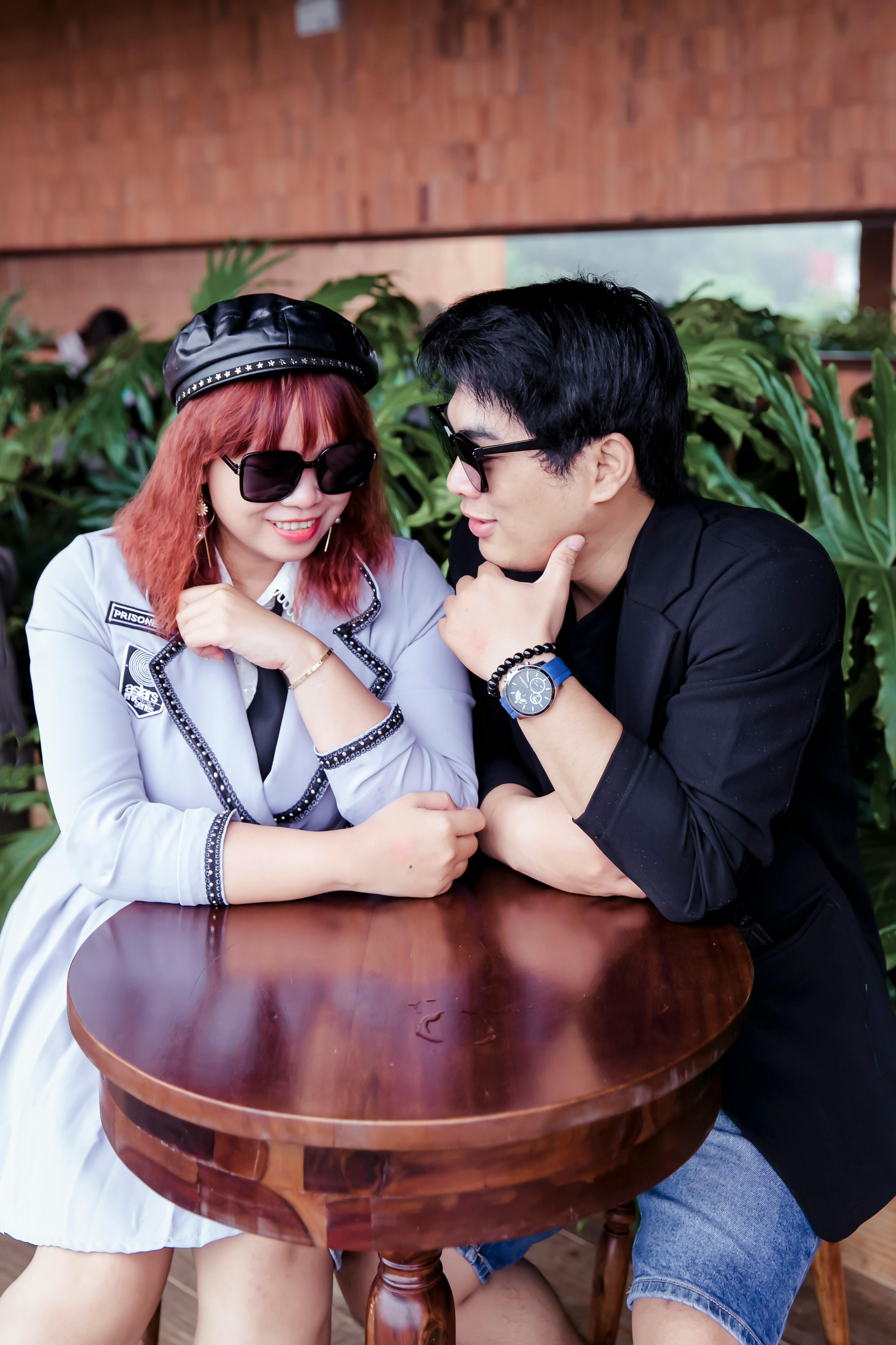 Two young adults in sunglasses enjoying a flirty conversation at a café.
