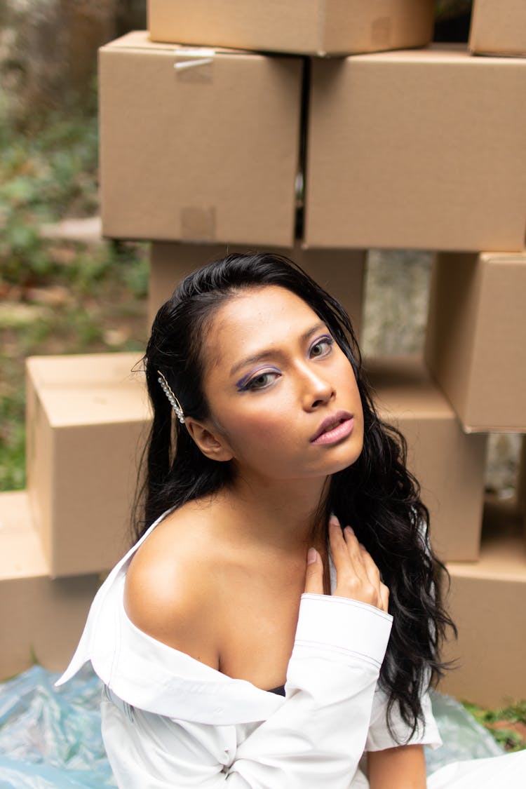 Woman Sitting Beside Pile Of Cardboard Boxes