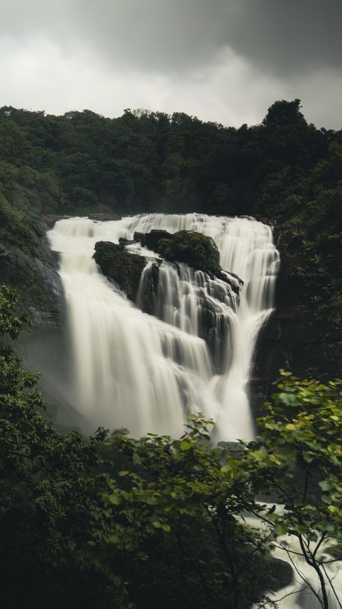 Free Stunning waterfall cascading amidst lush jungle landscape, creating a dramatic natural scene. Stock Photo