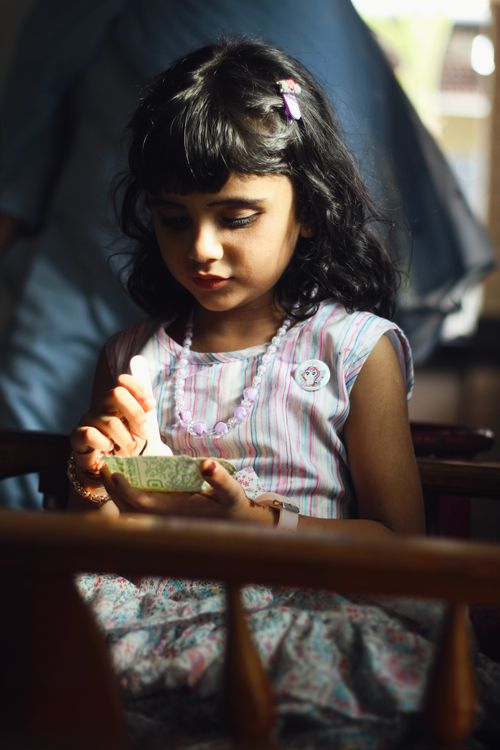 Free A young girl enjoying ice cream in sunlight, seated indoors, Nilambur. Stock Photo