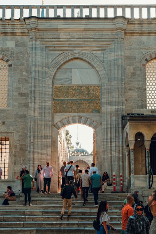 Free People entering a historic mosque in Istanbul, Turkey, through an ornate gate. Stock Photo