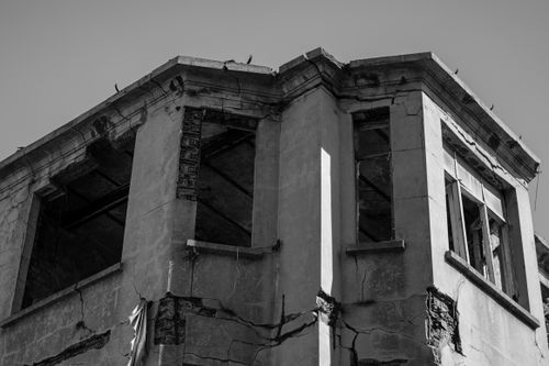 Free Black and white image of an abandoned derelict building with crumbling walls and broken windows. Stock Photo