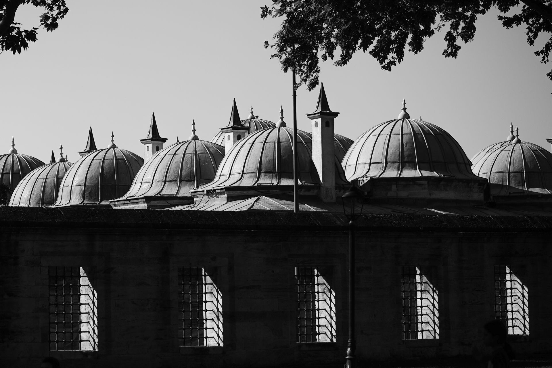 Black and white photo showcasing domed roofs and spires of a historic architectural structure, outdoors.