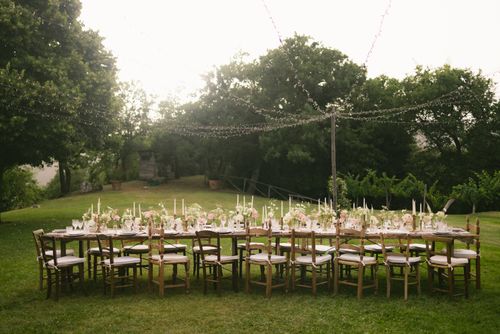 Free Beautiful outdoor wedding reception table setup with floral decorations and string lights in a garden. Stock Photo