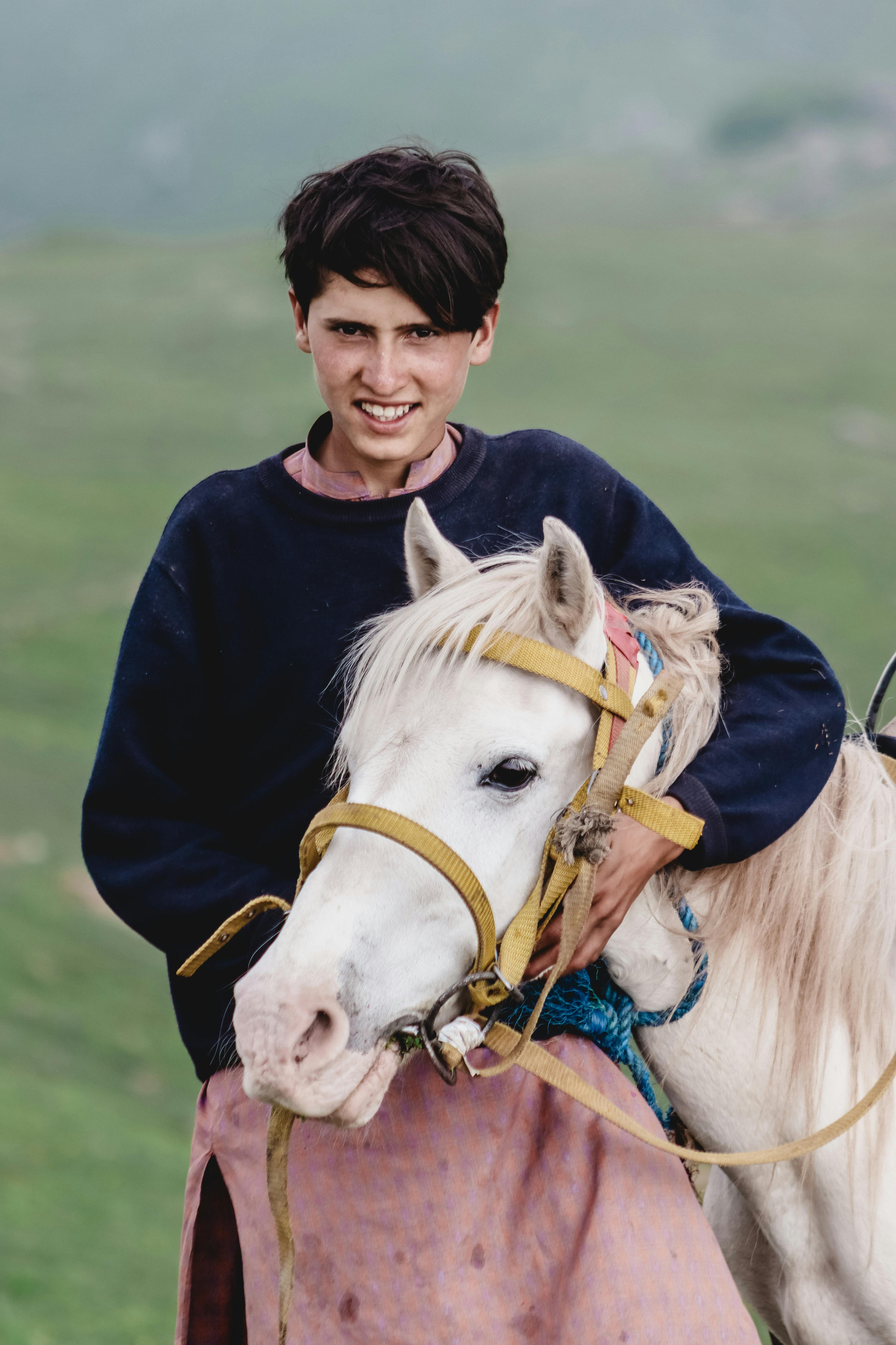 A young person posing with a white horse in the scenic hills of Naran, Pakistan.