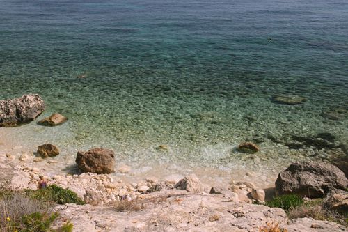 Free A tranquil rocky beach with clear turquoise waters under the summer sun, perfect for travel and relaxation. Stock Photo