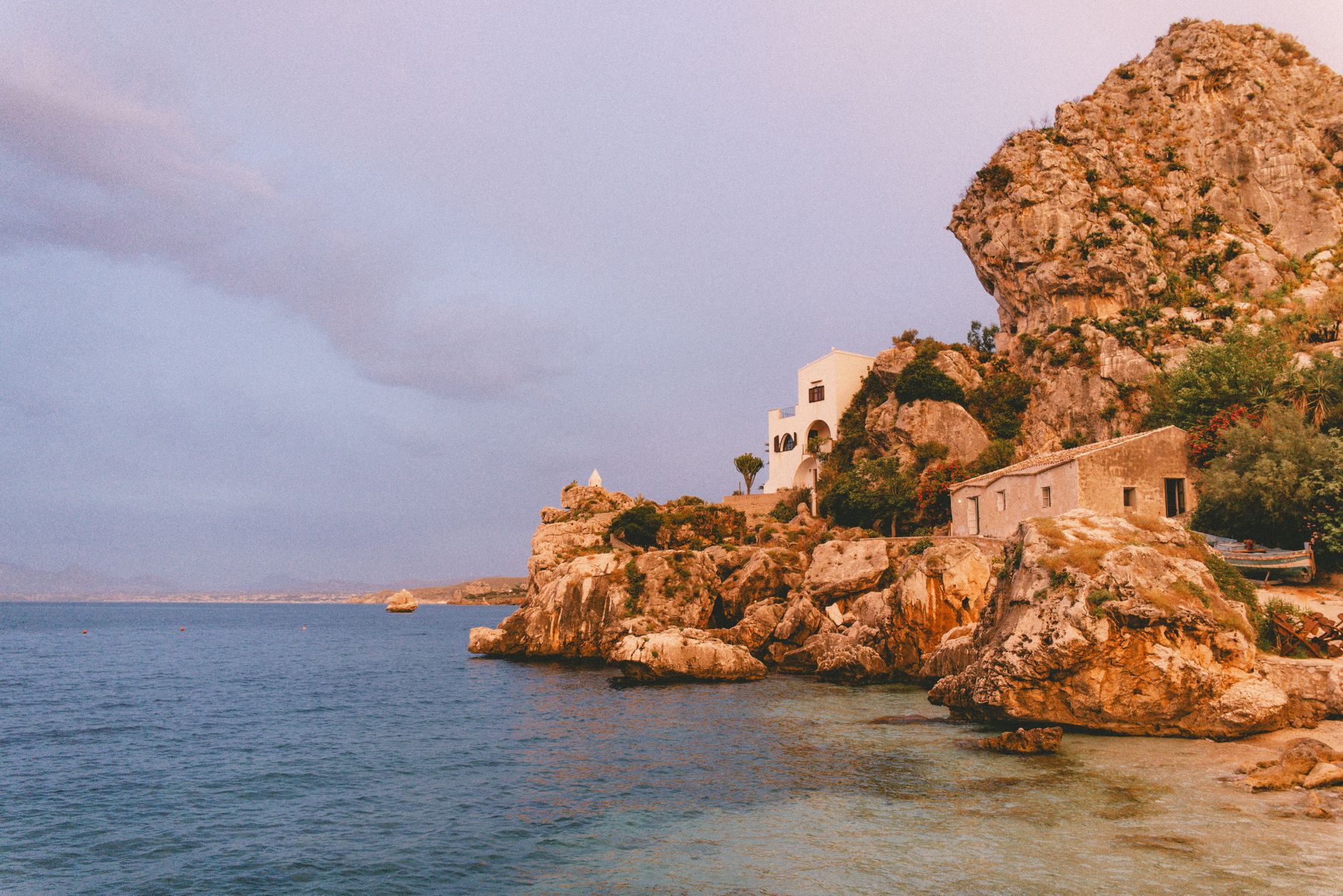 Illustrative rocky coastline in Sicily beside calm blue water
