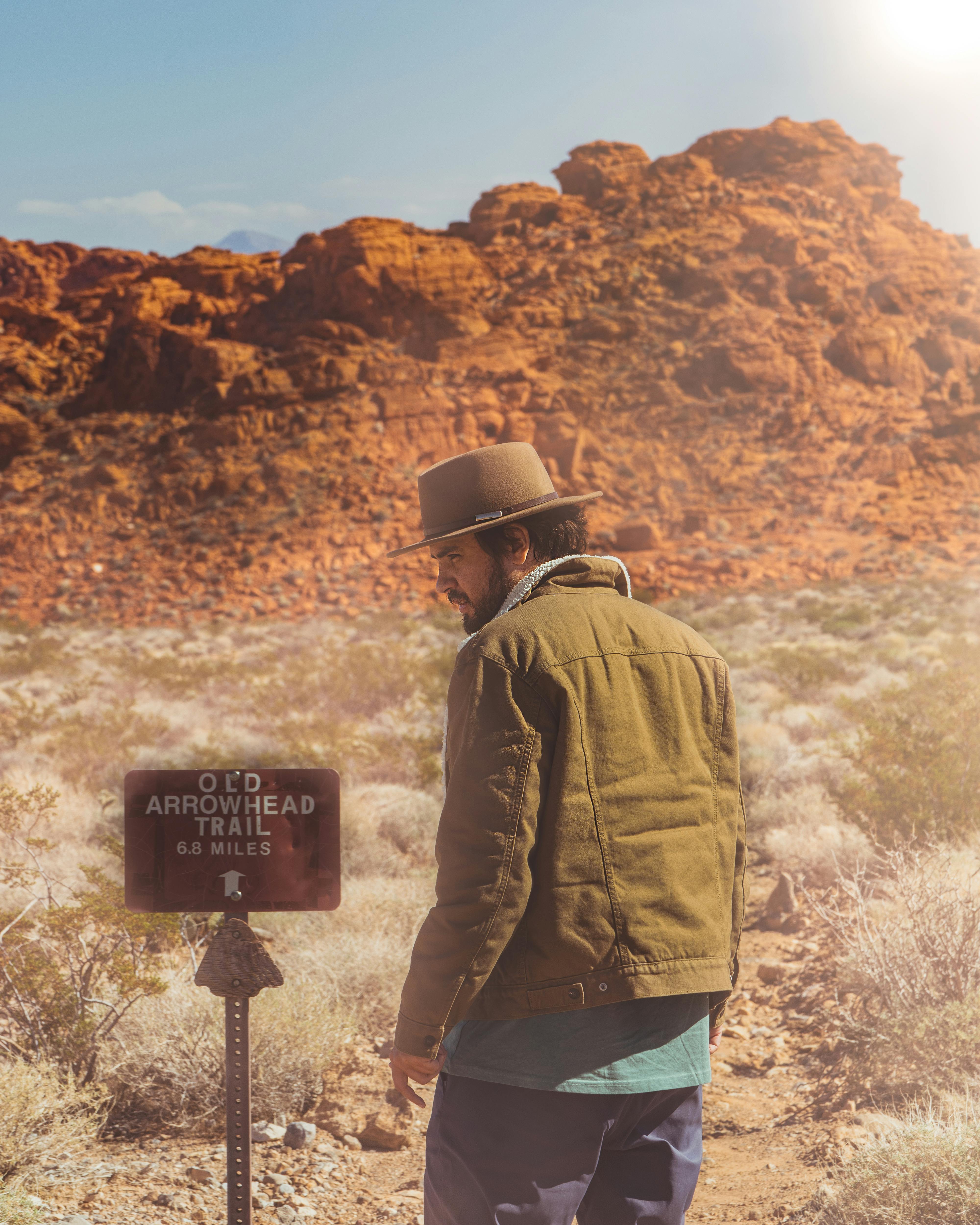 A man in a cowboy hat explores the Old Arrowhead Trail in a desert landscape during the day.