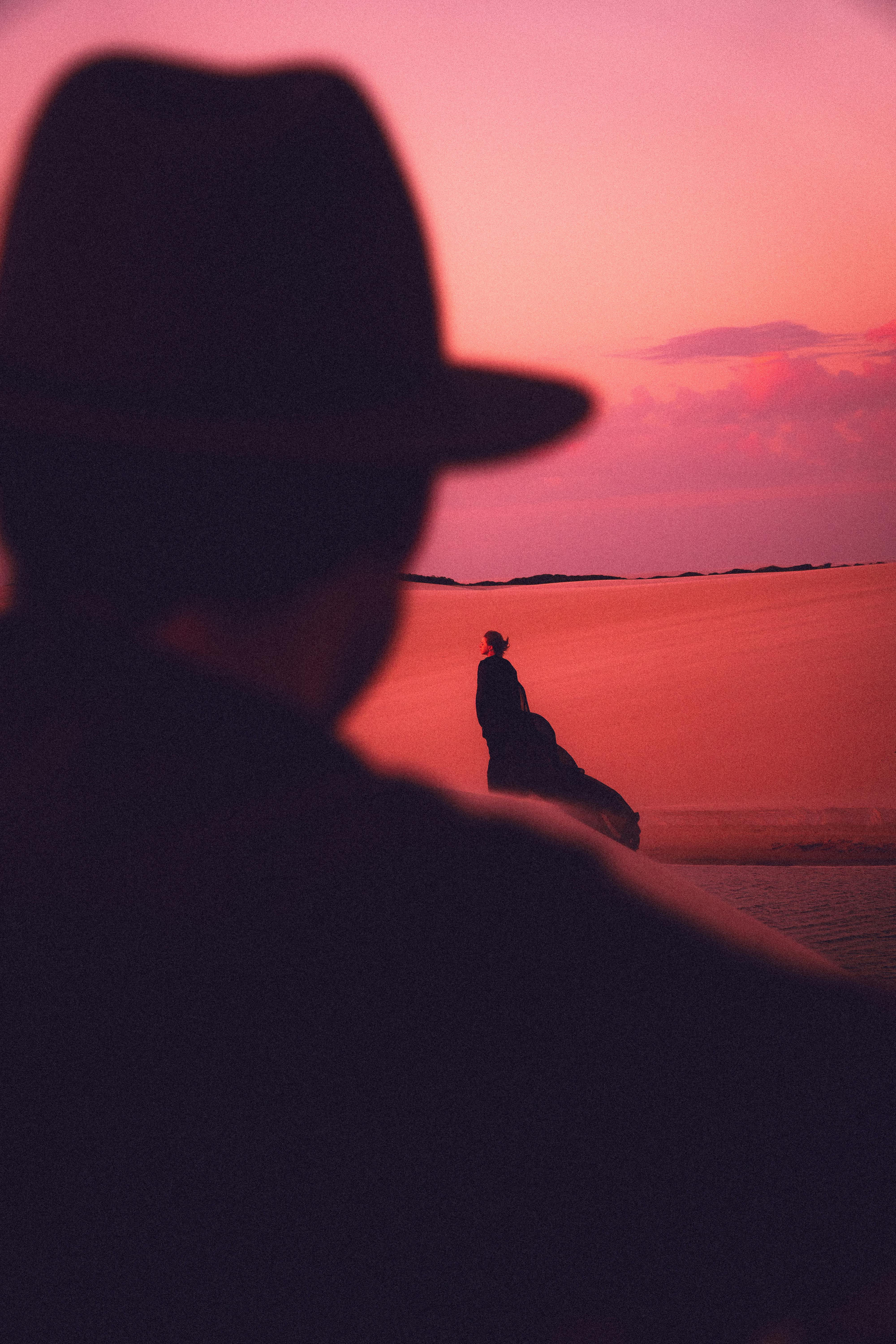 A mysterious silhouette in the dunes of Atins, Brazil under a vibrant pink sunset sky.