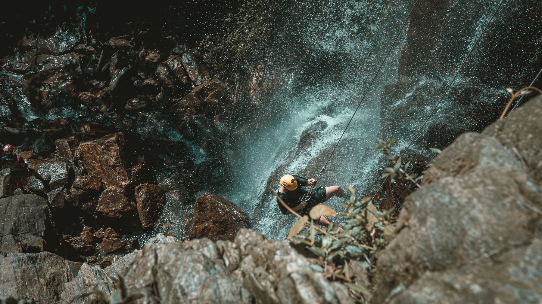 Experience the excitement of waterfall rappelling with an adventurous climber descending a rocky cliffside.
