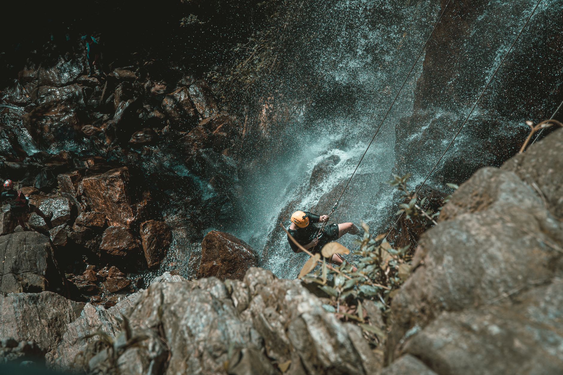 Experience the excitement of waterfall rappelling with an adventurous climber descending a rocky cliffside.