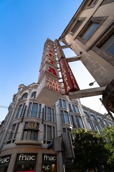 Low-angle view of historic building and signs in Porto, Portugal, under a clear blue sky.