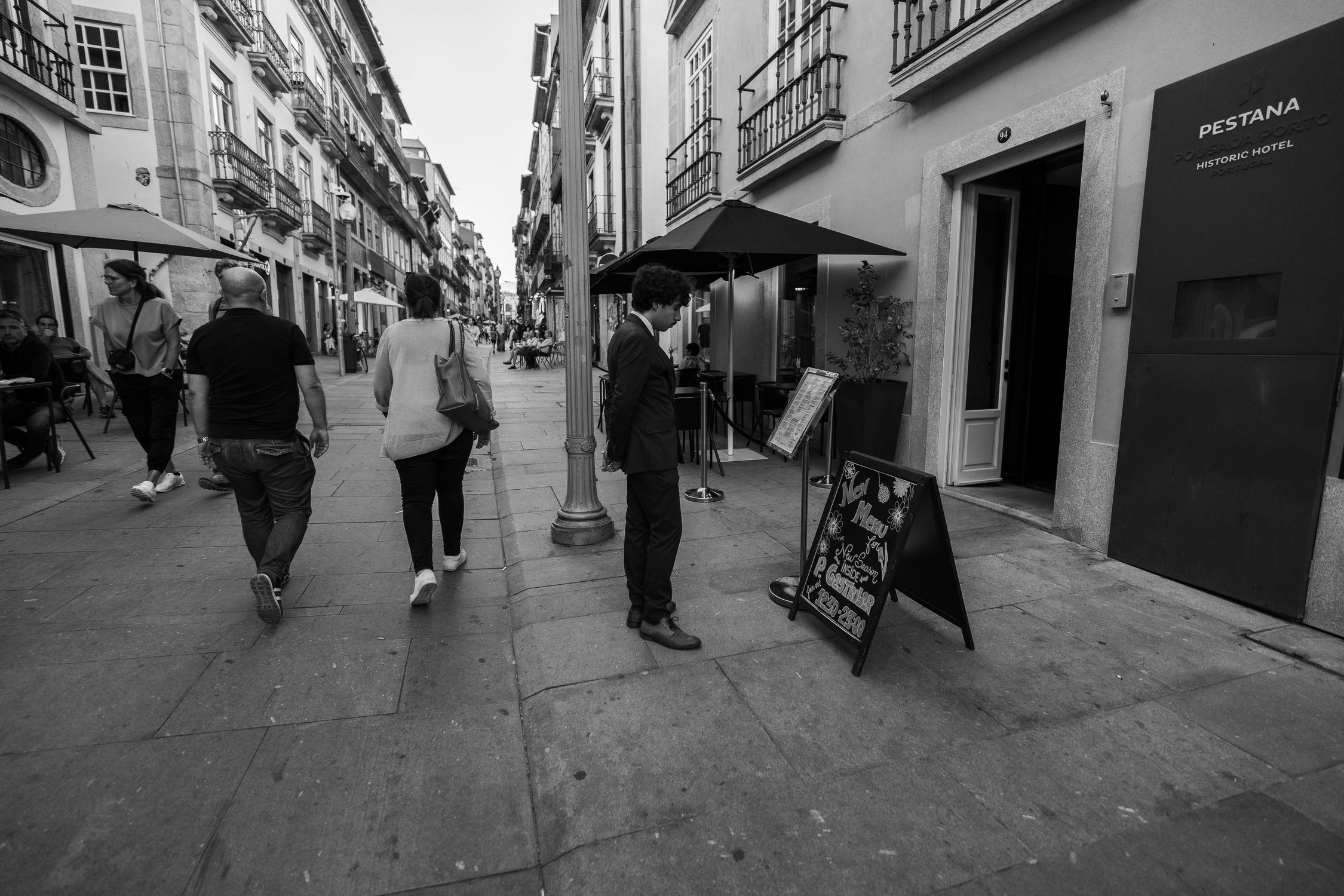 Black and white photo of people walking in a historic street of Porto, Portugal.