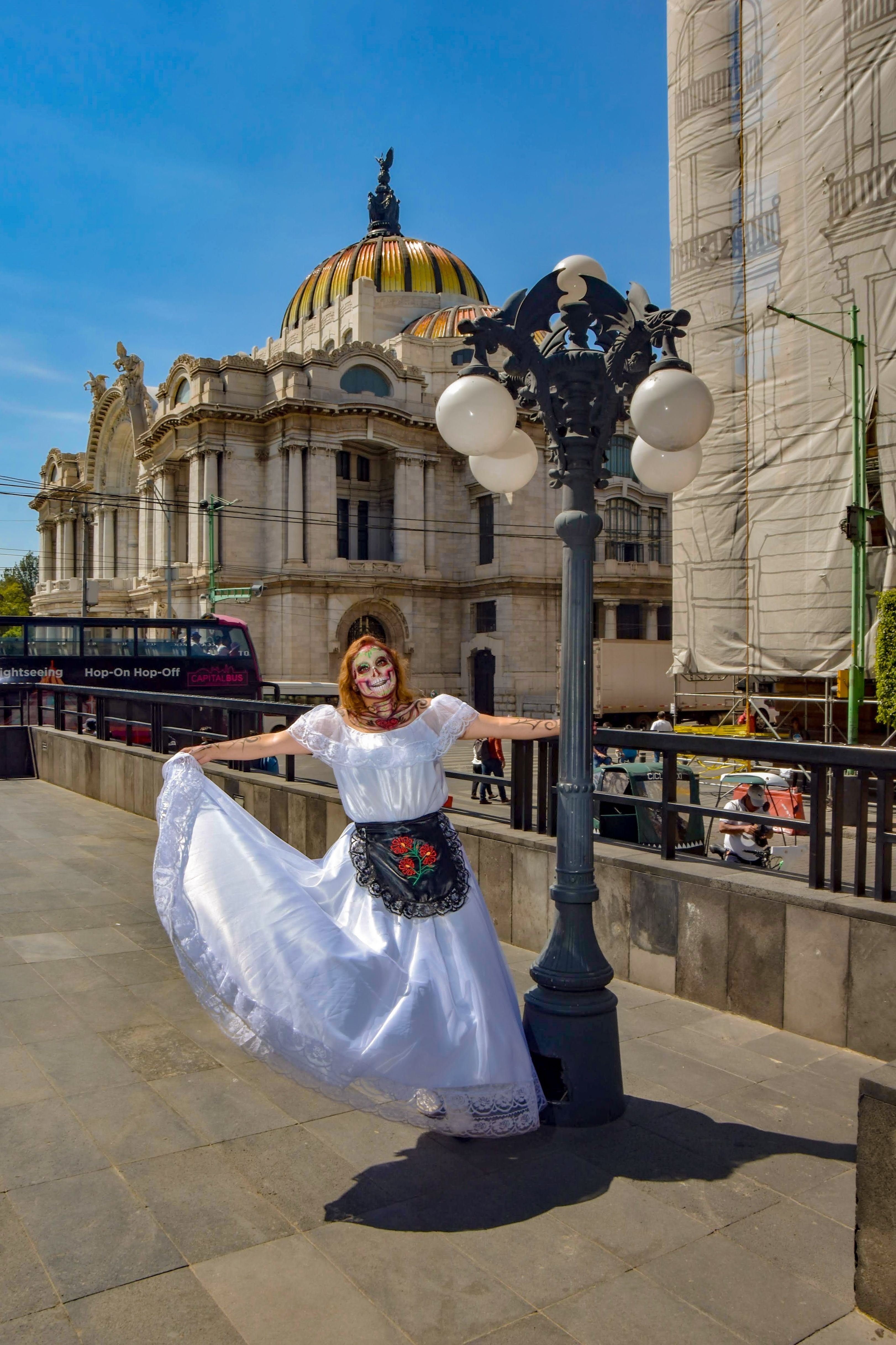 Woman in a White Dress and Makeup Posing on a Sidewalk · Free Stock Photo