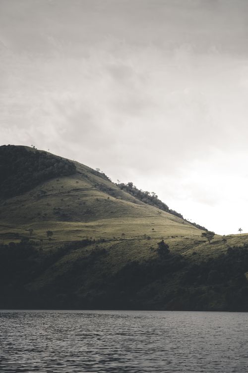 Free Tranquil landscape photo showcasing a green mountain slope at dusk, reflected in a calm lake below. Stock Photo