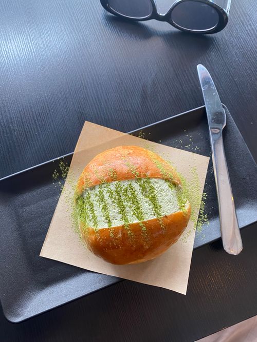 Free Delicious brioche bun served with matcha dusting, photographed on a black plate. Stock Photo