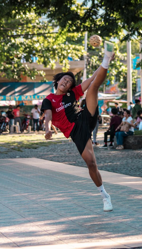Jovem a rematar numa partida de rua