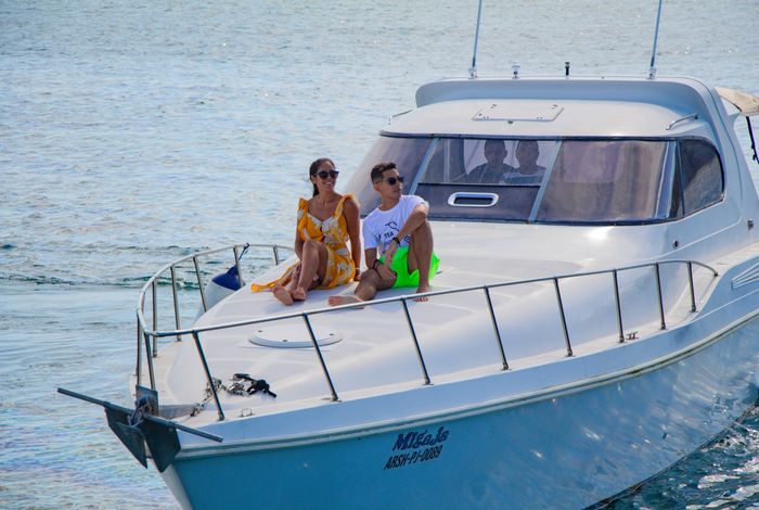 Couple sitting on the bow of a white motor yacht