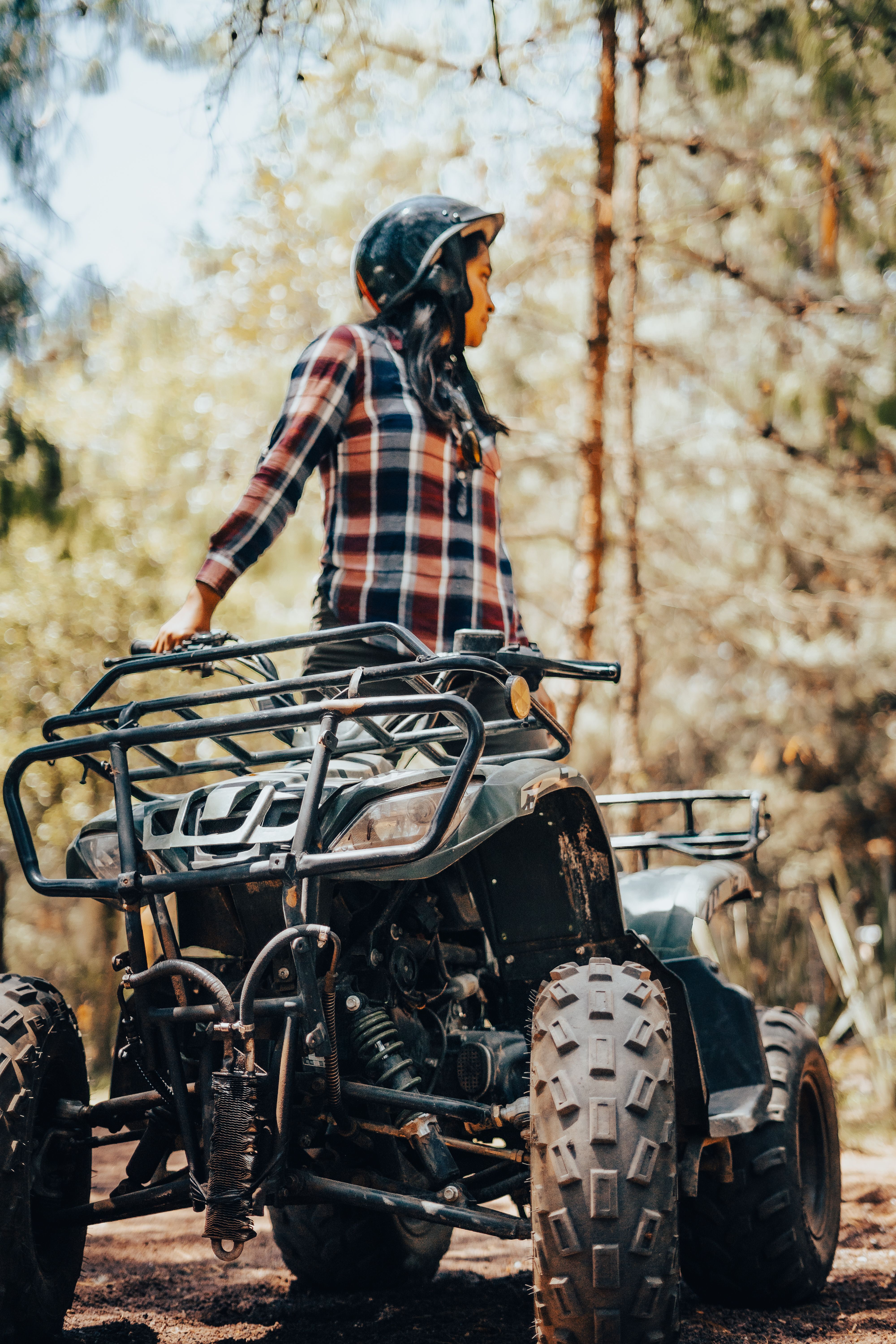 Woman in helmet explores the forest on an ATV, showcasing adventurous spirit in nature.