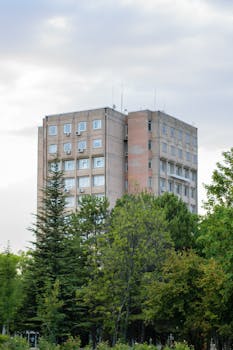 A contemporary apartment building amidst lush trees in an urban setting.
