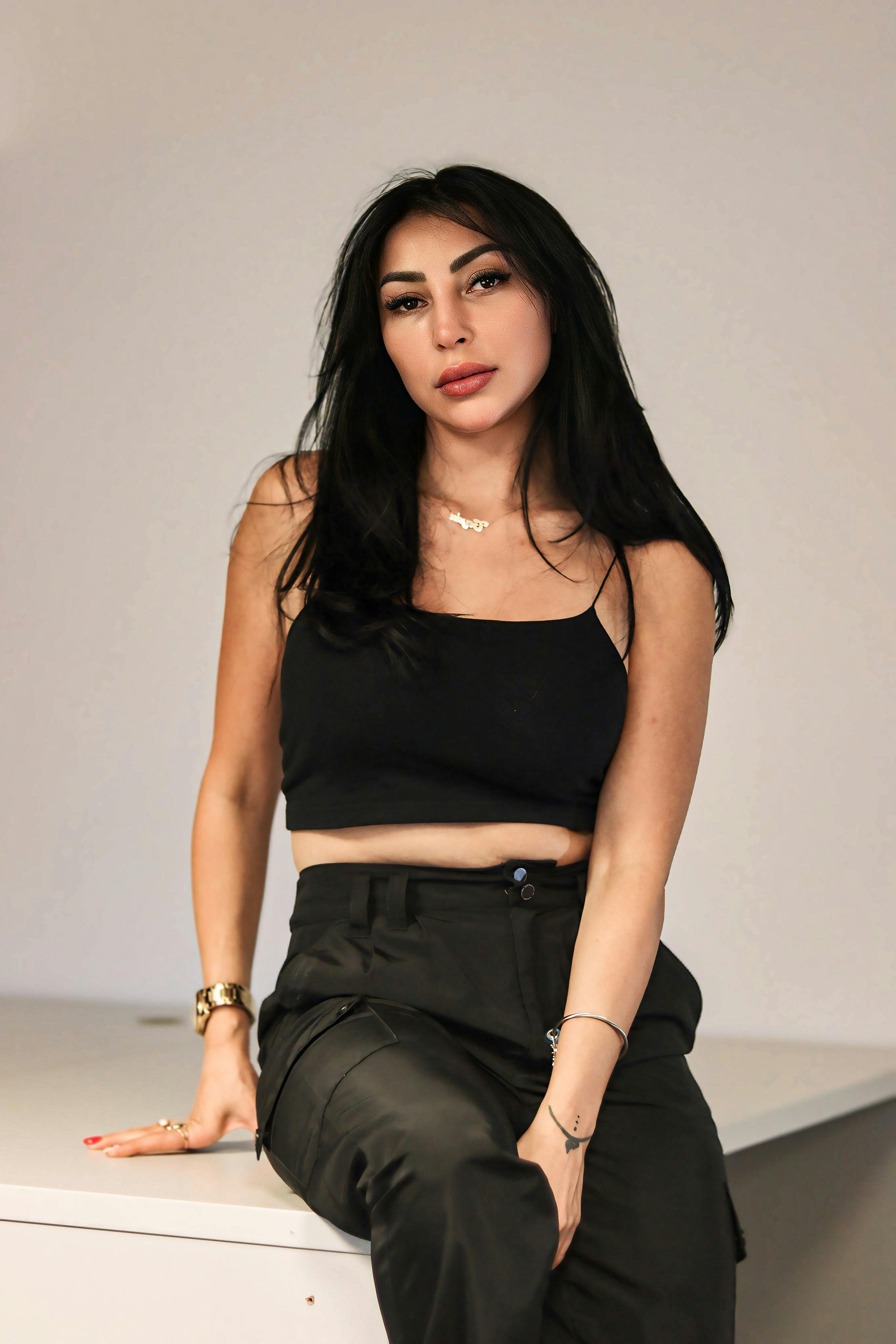 Stylish young woman posing indoors in a trendy crop top and trousers, showcasing modern fashion aesthetics.