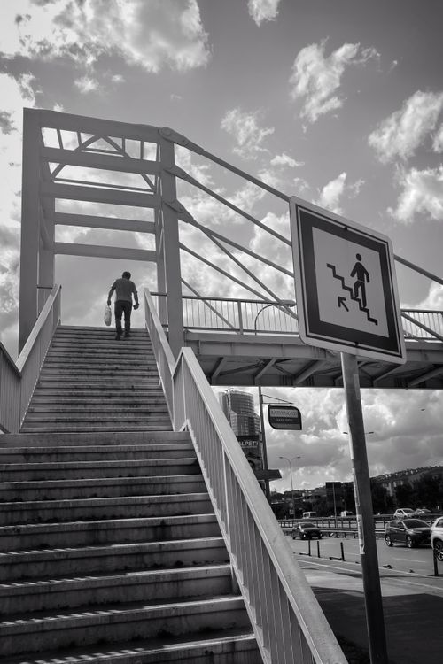 Free Man climbing pedestrian bridge stairs in a city, black and white photo. Stock Photo