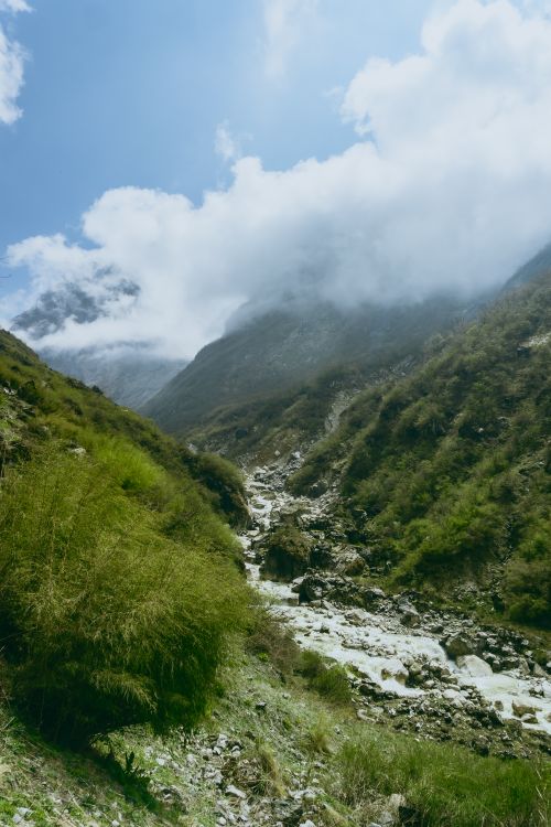 Free Scenic mountain valley with a stream and lush greenery under cloudy skies. Stock Photo