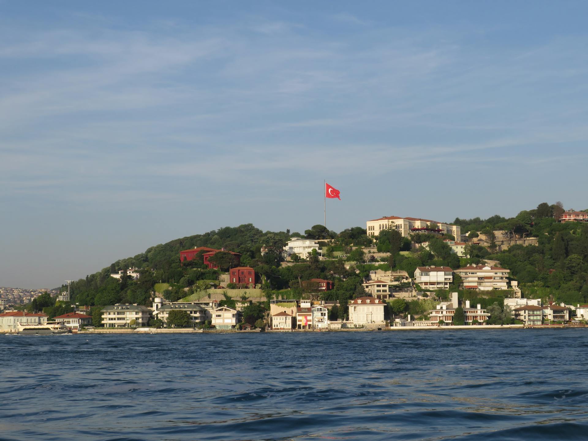 A beautiful landscape view showcasing Istanbul's Bosphorus coastline and Turkish flag on a sunny day.