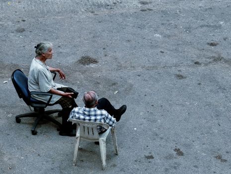 An elderly couple enjoys a quiet moment seated outdoors on the street in Beirut, Lebanon.