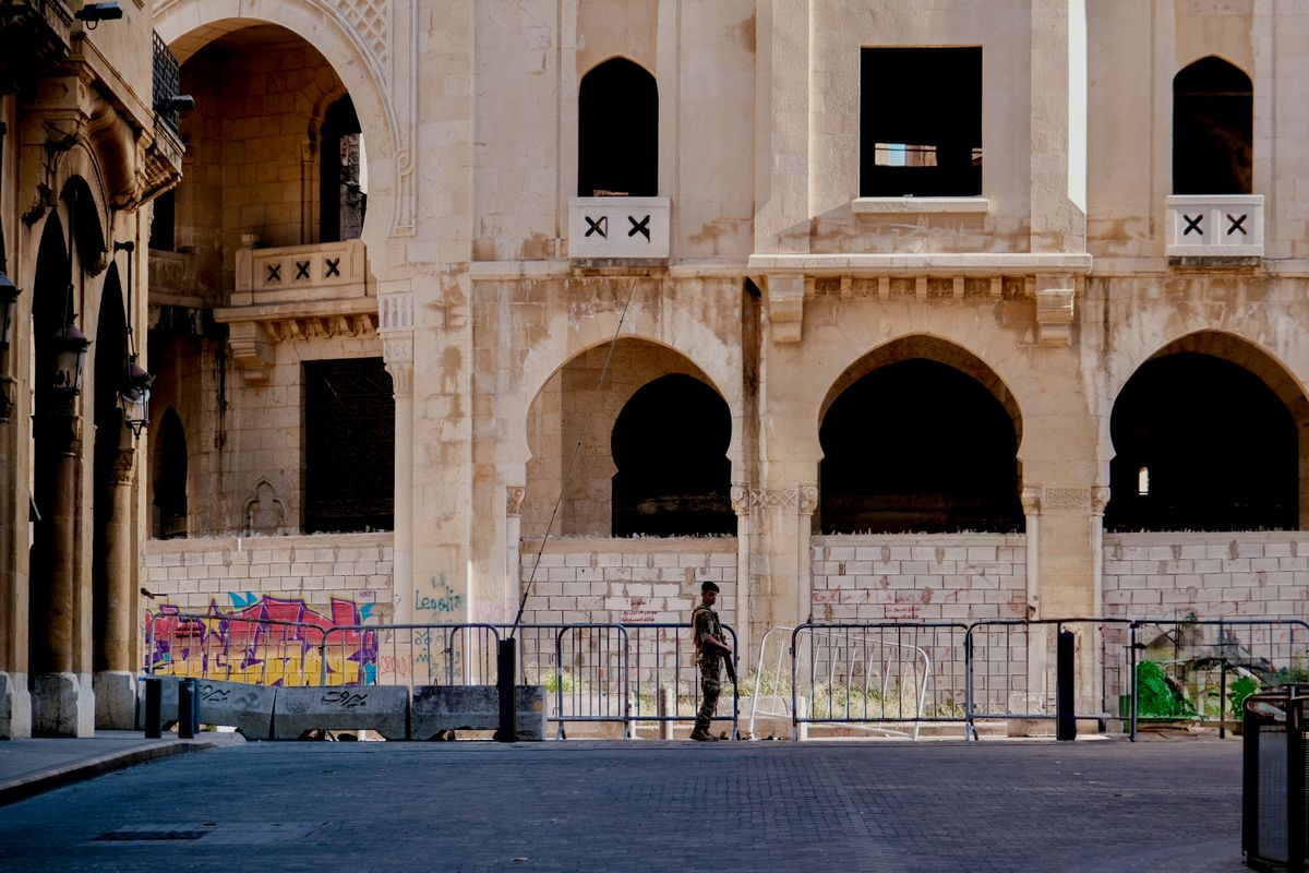 A soldier stands in front of a historical building in Beirut, Lebanon, highlighting urban architecture.