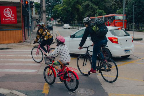 Free A family biking through a city intersection on a cloudy day, wearing helmets for safety. Stock Photo
