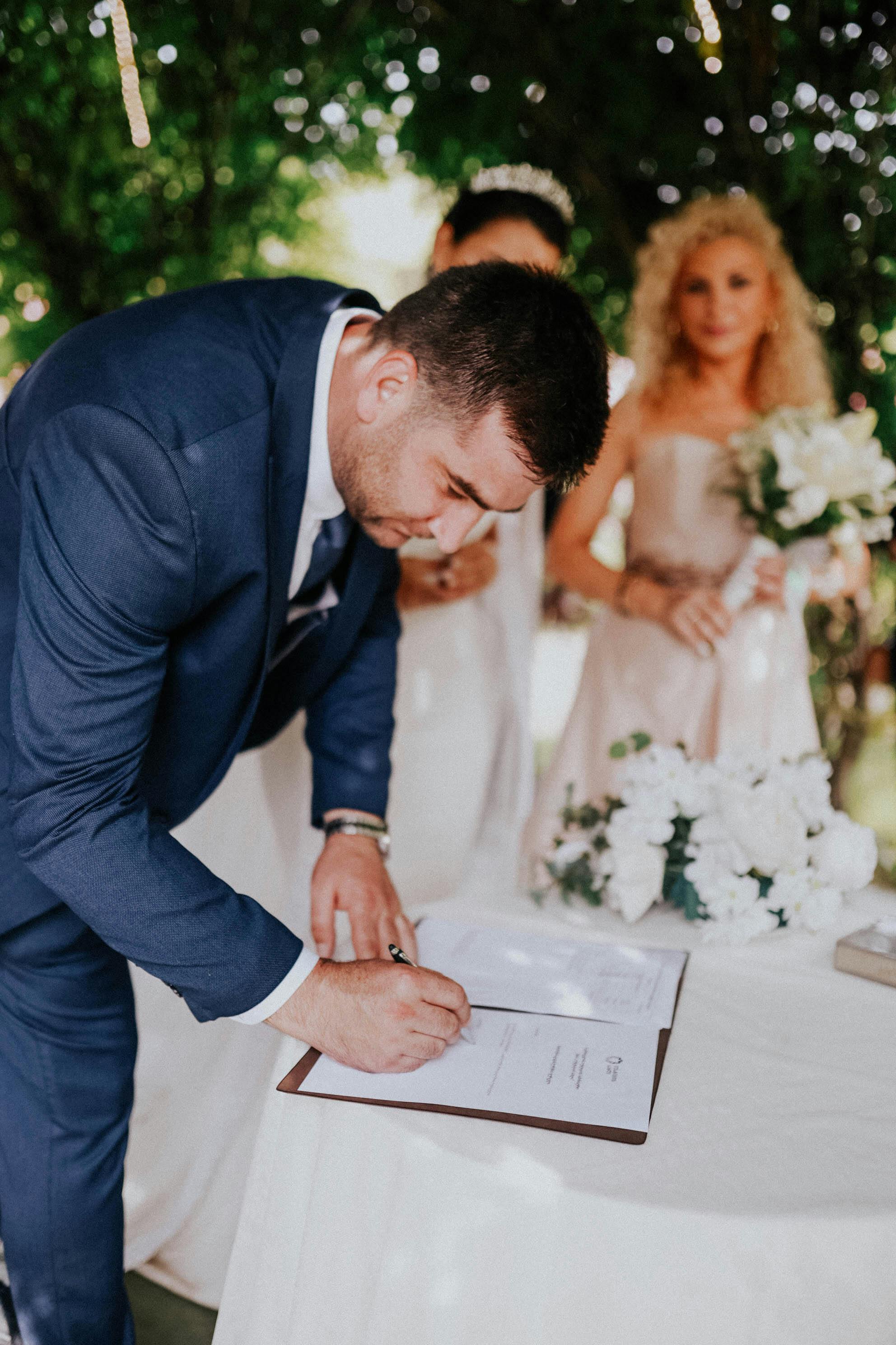 a groom signing the marriage certificate in the garden