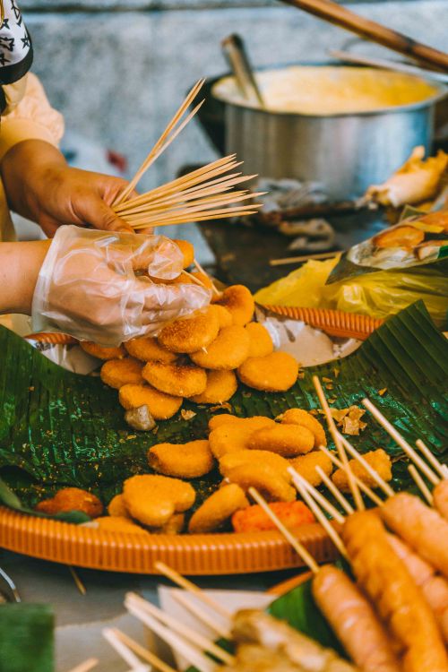 Free A street vendor prepares skewered fried snacks at an outdoor market in Kuala Lumpur, Malaysia. Stock Photo