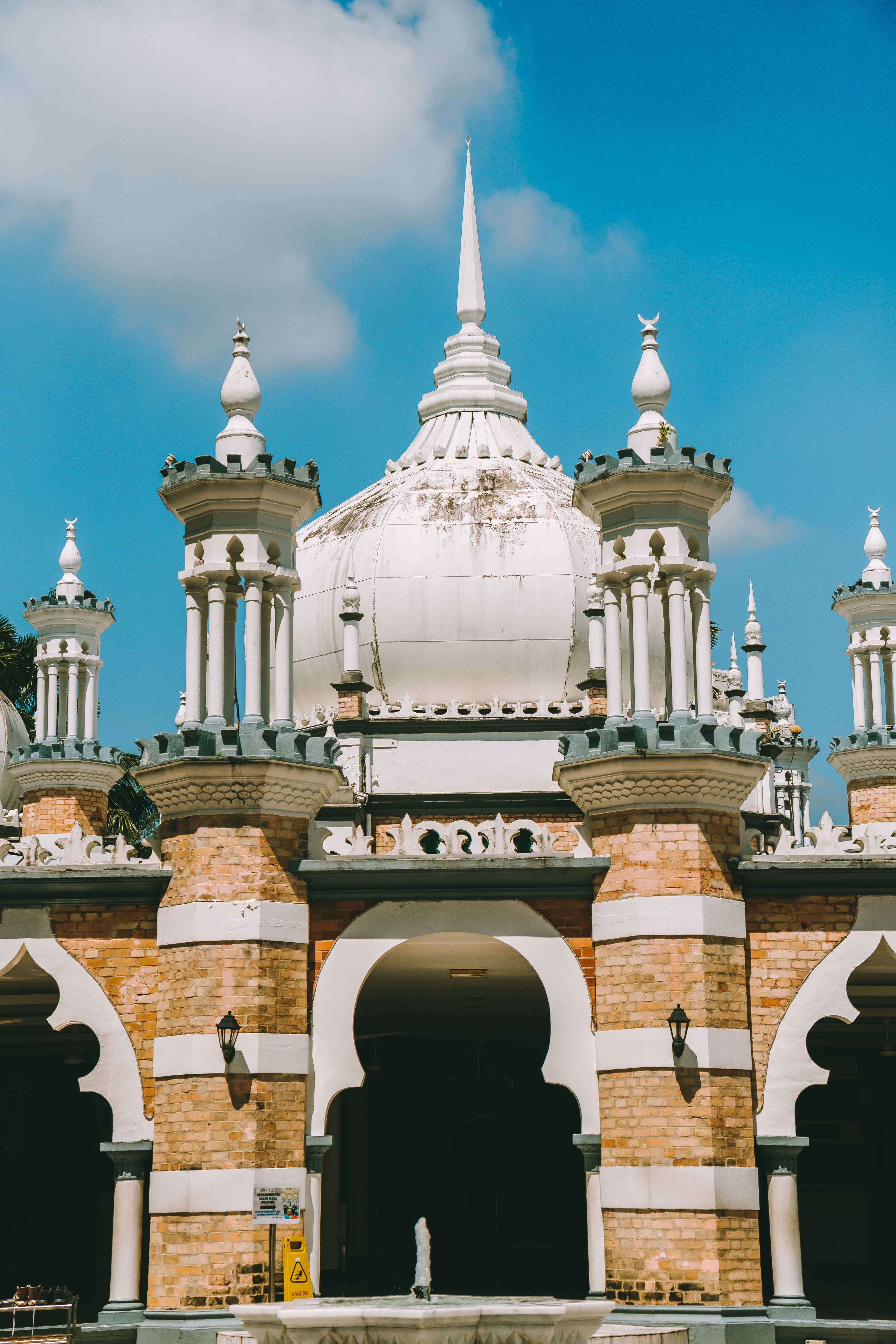 Close-up of intricate Mughal architecture details on the Sultan Abdul Samad Jamek Mosque in Kuala Lumpur, Malaysia under a clear blue sky