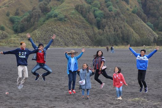 Group of people joyfully jumping outdoors with scenic hills in the background, conveying energy and happiness.