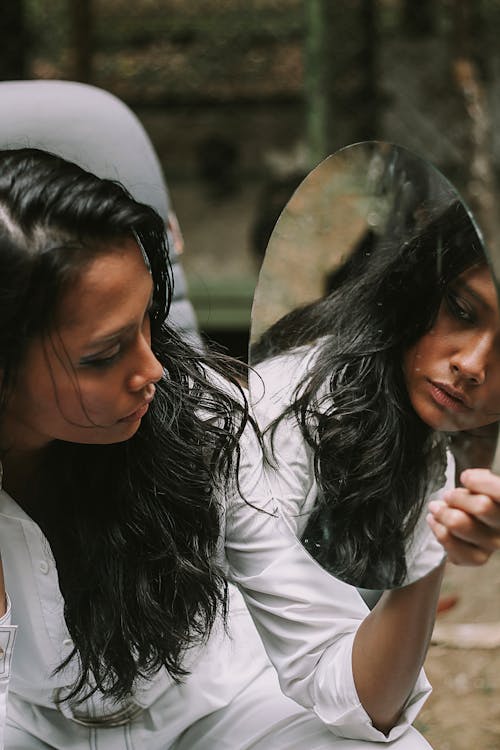 Photo of Woman Holding and Looking at a Mirror