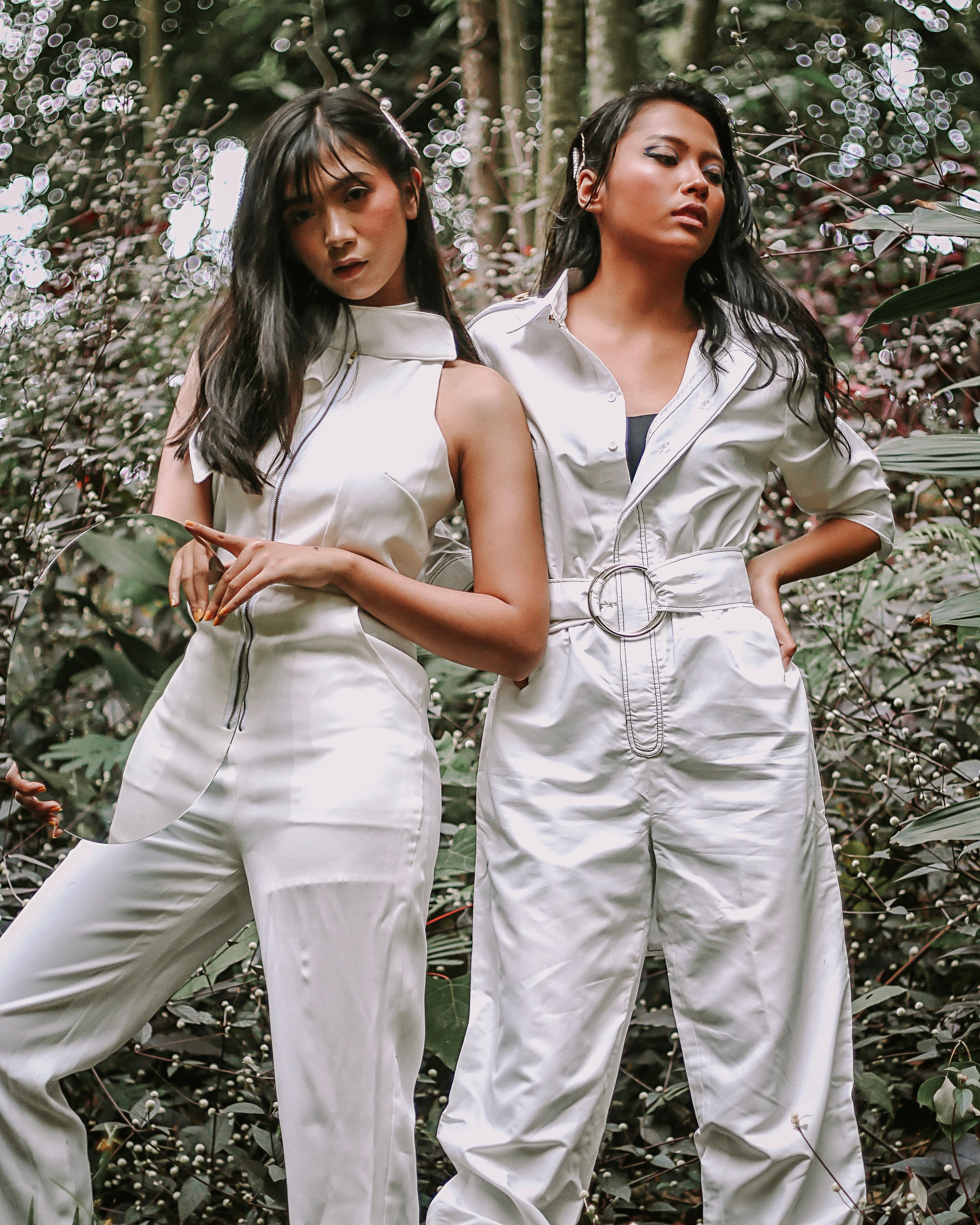 Modelos de moda posando em macacões estilosos entre a vegetação tropical.