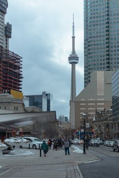 Vibrant downtown Toronto scene highlighting the CN Tower with people on a city street in winter.