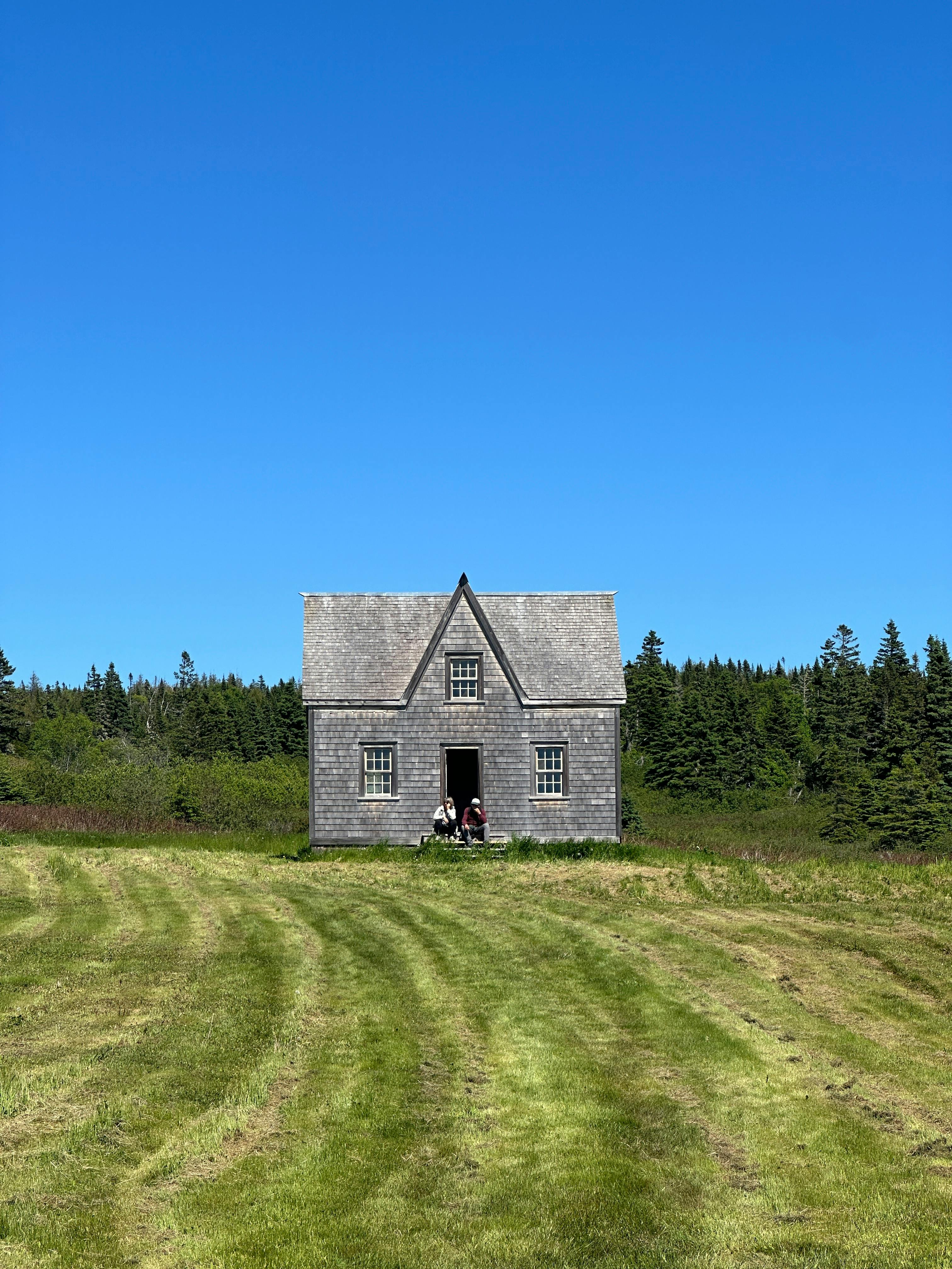 Explore the serene countryside with a rustic house amidst lush greenery and clear blue skies.